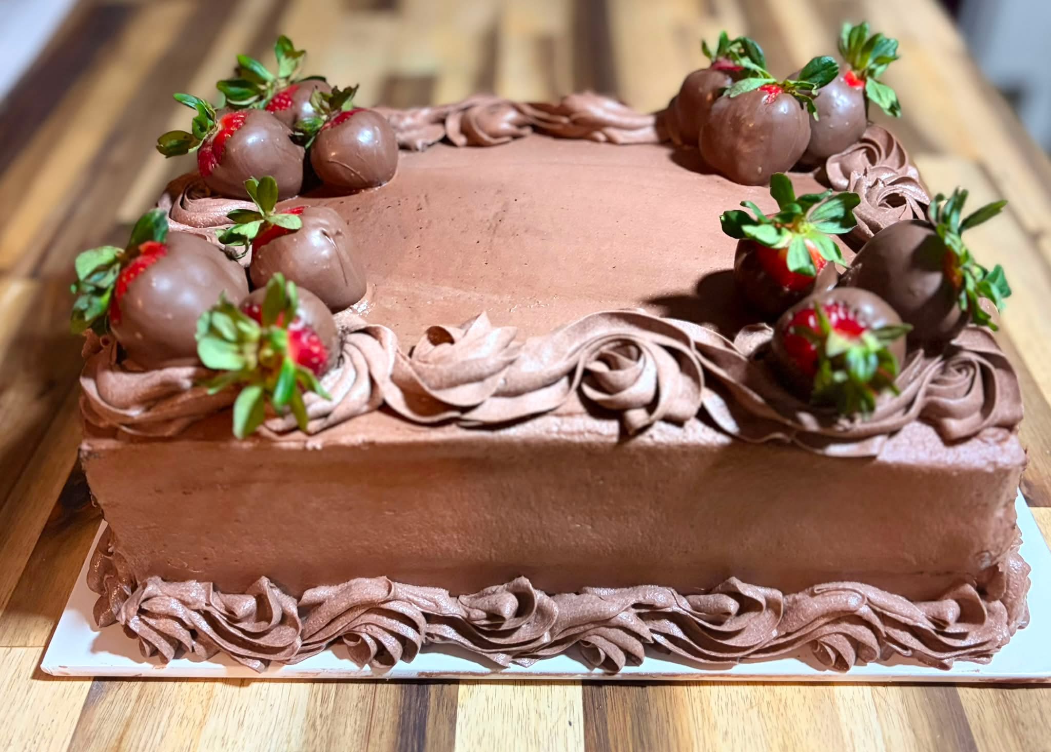 Chocolate frosted celebration cake with chocolate-covered strawberries